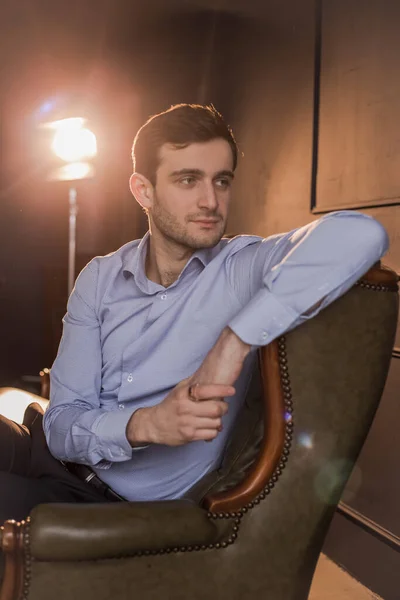 Gömlekli Gürcü bir adam eski bir sandalyede oturur.