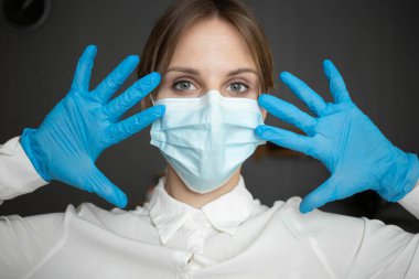 A nurse wearing a protective mask and gloves shows all her fingers