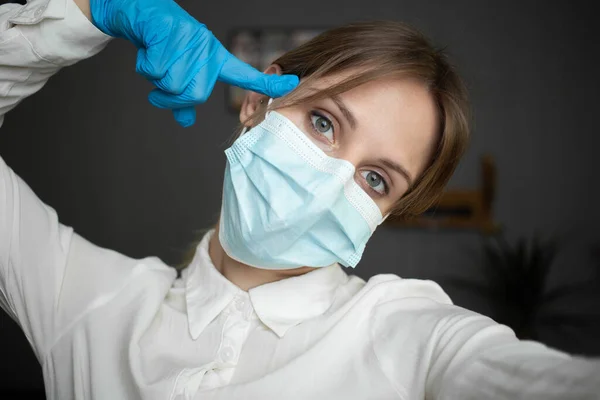 A nurse wearing a protective mask and gloves points to her head