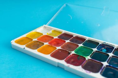 Mavi arka planda fırçalar, boya araçları ve boyalar