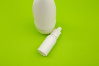Beyaz deodorant ve parlak yeşil arka planda beyaz şişe.