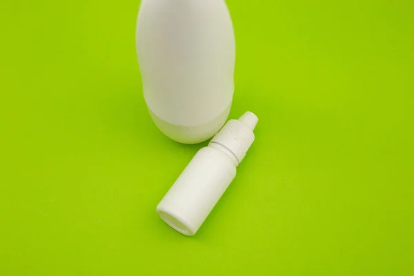 White deodorant and white bottle on a bright green background