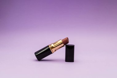 Mor bir arka planda, şişedeki ruj.