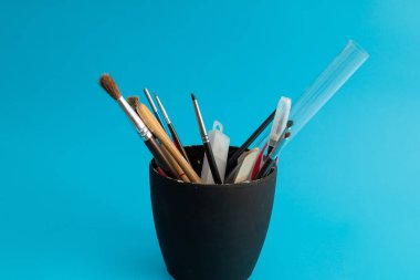 Mavi arka planda fırçalar, boya araçları ve boyalar