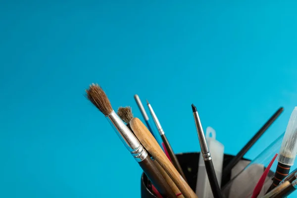 Brushes, painting tools and paints on a blue background