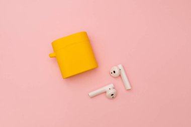 Pembe arka planda kablosuz kulaklık, özne çekimi.