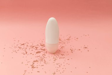 Pembe arka planda beyaz bir şişede patenli deodorant