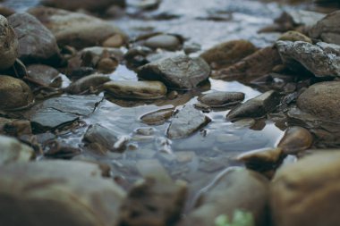 Su kayaların arasından akar.