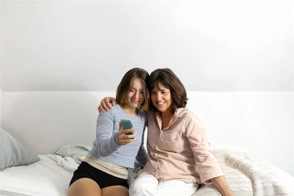 Anne ve kızı cep telefonuna bakarken birlikte komik anlar yaşıyorlar.