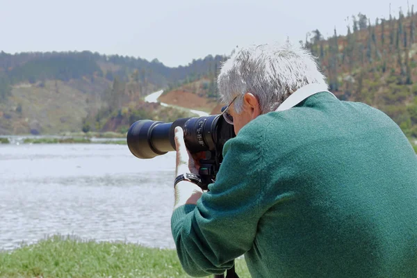 Adam fotoğraf çekerken telefon lensini odaklıyor.