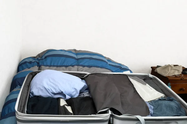 Open suitcase on a bed with clothes stored in an untidy way