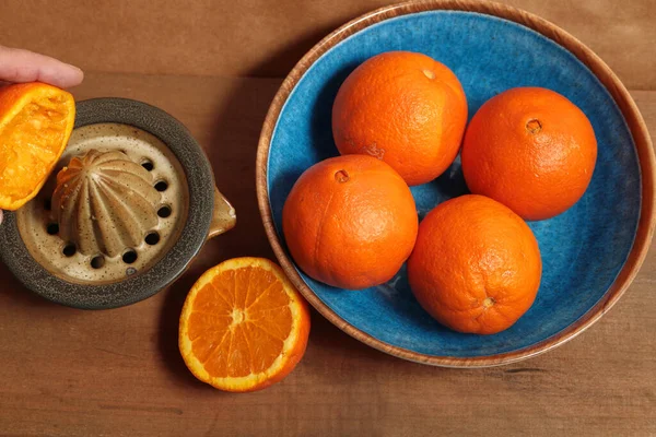 Traditional preparation of orange juice using a manual extractor. ceramic and wood materials