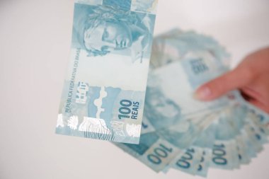 Siyah cüzdan ve mavi el ile 100 reais banknot.