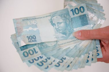 Siyah cüzdan ve mavi el ile 100 reais banknot.