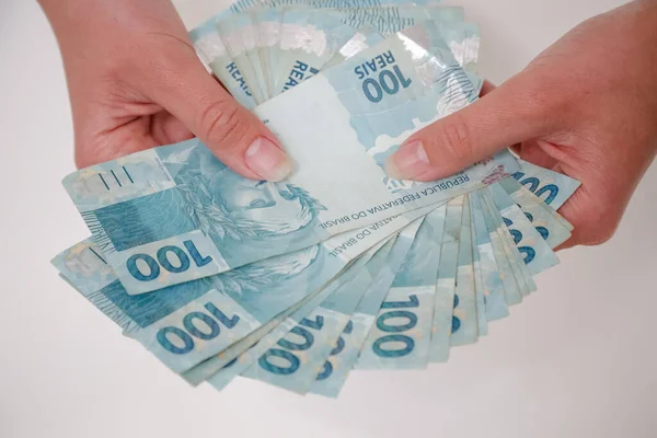 Siyah cüzdan ve mavi el ile 100 reais banknot.