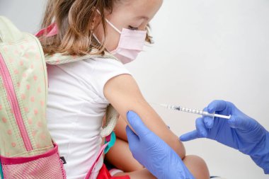 Child being vaccinated against covid 19 goes back to medical school with blue glove and syringe.