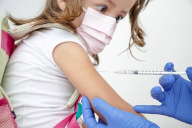 Child being vaccinated against covid 19 goes back to medical school with blue glove and syringe.