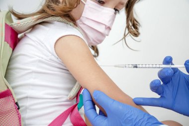 Child being vaccinated against covid 19 goes back to medical school with blue glove and syringe.