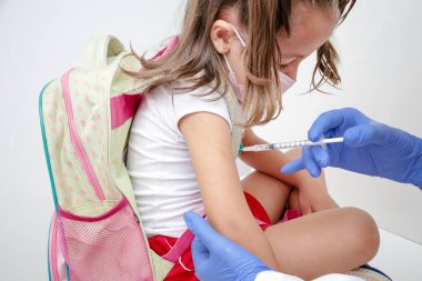 Child being vaccinated against covid 19 goes back to medical school with blue glove and syringe.