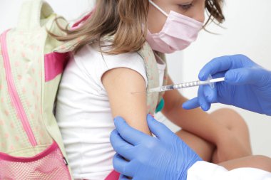 Child being vaccinated against covid 19 goes back to medical school with blue glove and syringe.