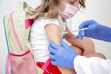 Child being vaccinated against covid 19 goes back to medical school with blue glove and syringe.