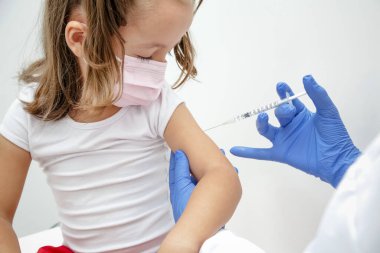 Child being vaccinated against covid 19 goes back to medical school with blue glove and syringe.