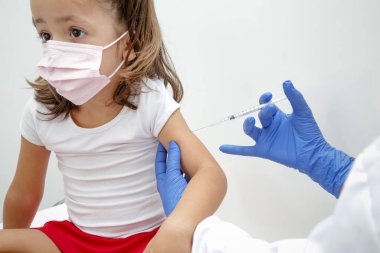 Child being vaccinated against covid 19 goes back to medical school with blue glove and syringe.