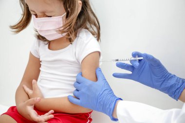 Child being vaccinated against covid 19 goes back to medical school with blue glove and syringe.