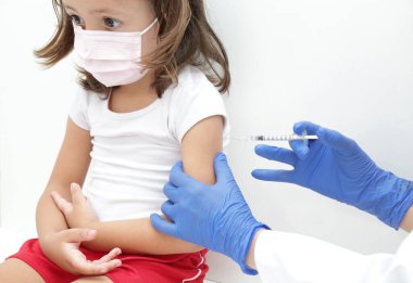 Child being vaccinated against covid 19 goes back to medical school with blue glove and syringe.
