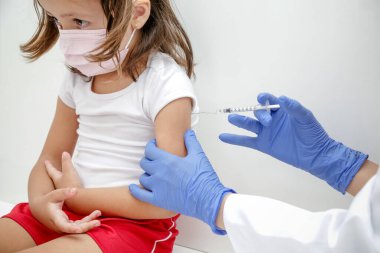 Child being vaccinated against covid 19 goes back to medical school with blue glove and syringe.