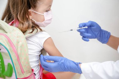 Child being vaccinated against covid 19 goes back to medical school with blue glove and syringe.