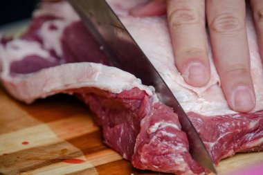 Arka planda keskin bıçakla masada sığır eti kesiyor..