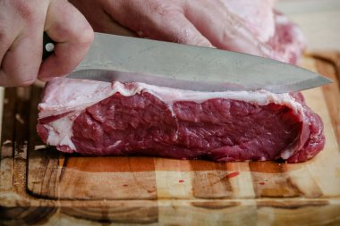 Arka planda keskin bıçakla masada sığır eti kesiyor..