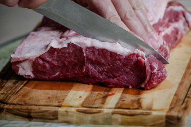 Arka planda keskin bıçakla masada sığır eti kesiyor..