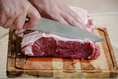 Arka planda keskin bıçakla masada sığır eti kesiyor..