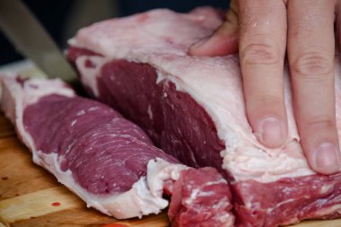 Arka planda keskin bıçakla masada sığır eti kesiyor..