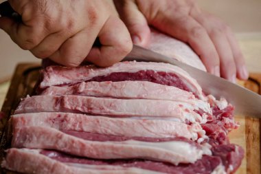 Arka planda keskin bıçakla masada sığır eti kesiyor..