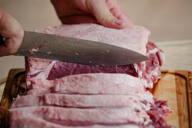 Arka planda keskin bıçakla masada sığır eti kesiyor..