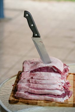 Arka planda keskin bıçakla masada sığır eti kesiyor..