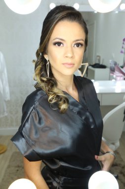 Güzel bir kadın aynanın önünde beyaz arka plan ışığı için makyaj yapıyor..