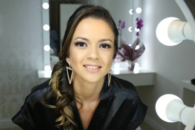 Güzel bir kadın aynanın önünde beyaz arka plan ışığı için makyaj yapıyor..