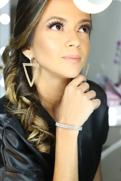 Güzel bir kadın aynanın önünde beyaz arka plan ışığı için makyaj yapıyor..