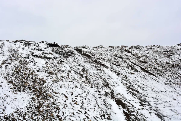 五彩斑斓的高山 陡峭的山岗位于道路两旁 冬季被白雪覆盖 在灰白的天空中 一片有趣而迷人的风景 — 图库照片