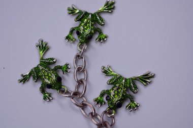 Küçük yeşil kurbağalarla süslenmiş güzel, parlak bir anahtarlık, küçük yeşil taşlı kurbağalar. Anahtarları dekore eden üç küçük kurbağadan oluşan metal bir zincirin mücevherleri..