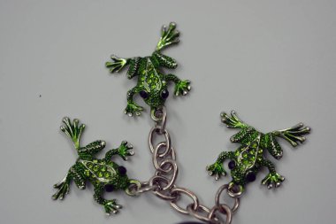 Küçük yeşil kurbağalarla süslenmiş güzel, parlak bir anahtarlık, küçük yeşil taşlı kurbağalar. Anahtarları dekore eden üç küçük kurbağadan oluşan metal bir zincirin mücevherleri..