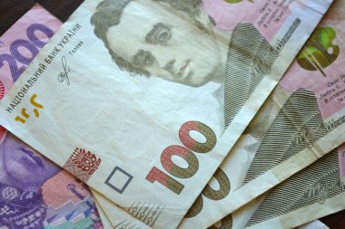 Bright, freshly printed money, large banknotes of 100 and 200 Ukrainian hryvnias. The money of Ukraine is located and laid out over the entire wooden surface.