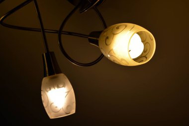 Ceiling lighting, lighting fixtures, a chandelier with lamps on hanging on the ceiling of one of the rooms.