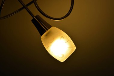 Ceiling lighting, lighting fixtures, a chandelier with lamps on hanging on the ceiling of one of the rooms.