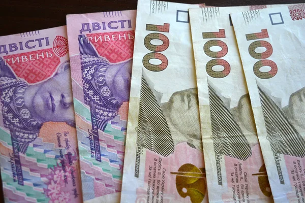 Bright, freshly printed money, large banknotes of 100 and 200 Ukrainian hryvnias. The money of Ukraine is located and laid out over the entire wooden surface.