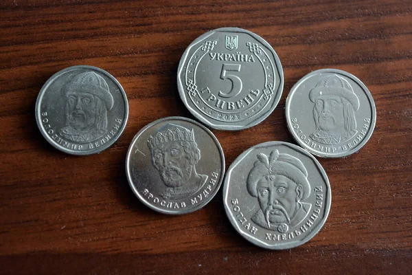 Ukrainian kopecks, small change in the amount of one 1, two 2, five 5 hryvnias are located on a dark brown table.